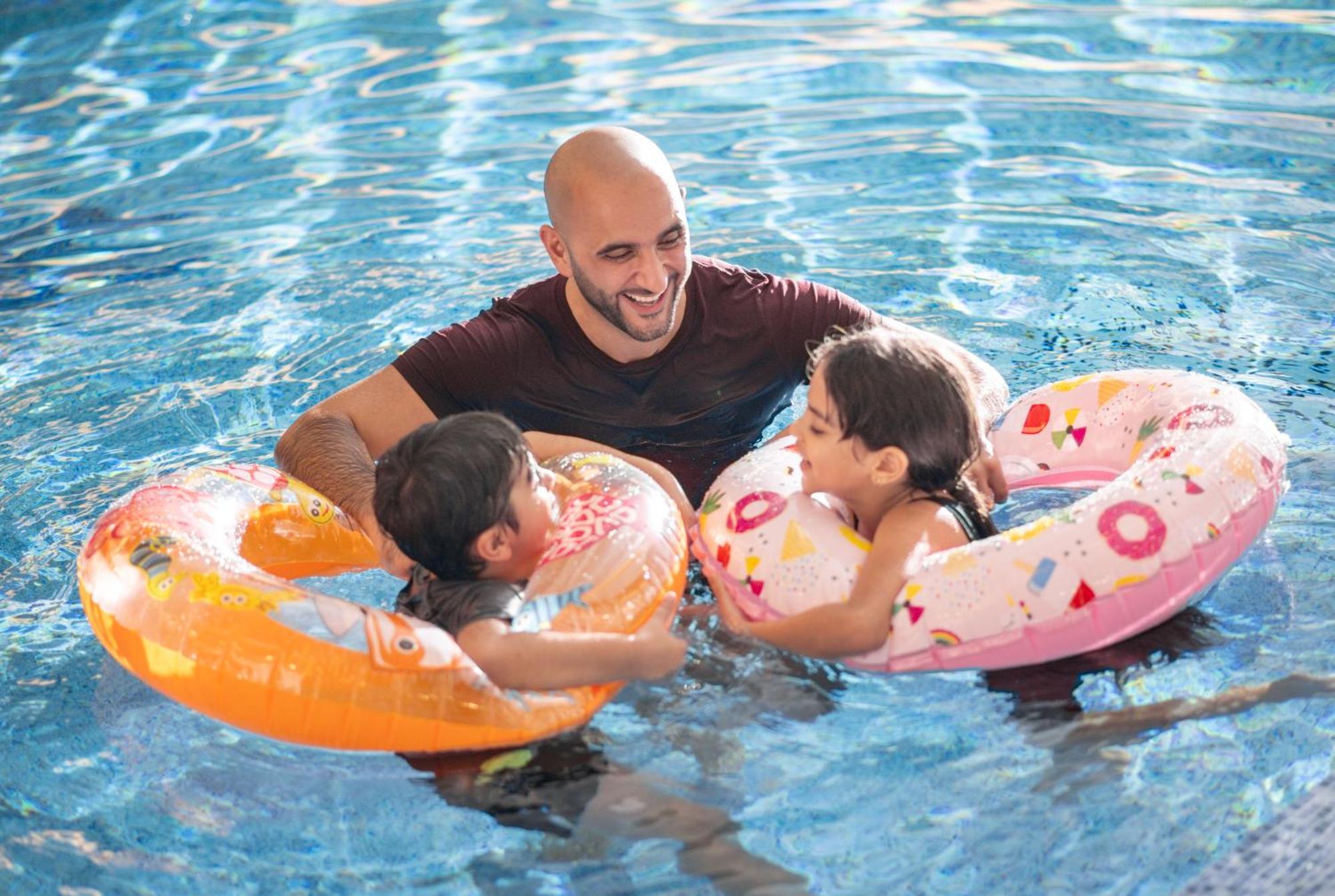 Delta Hotels By Marriott City Center Doha Bagian luar foto A father and two children in a swimming pool